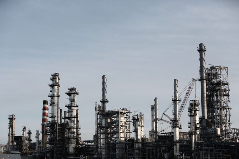 Skyline view of an industrial factory with tall chimneys against a clear sky.