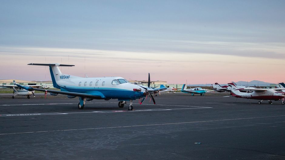 A serene view of private jets lined up on an airport runway during twilight.