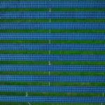 Aerial photograph of a solar farm featuring rows of solar panels and green spaces.
