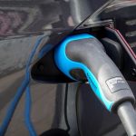 Close-up of an electric vehicle being charged using a Mennekes EV connector.