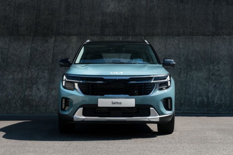 A modern blue Kia Seltos SUV parked against a concrete wall in daylight.