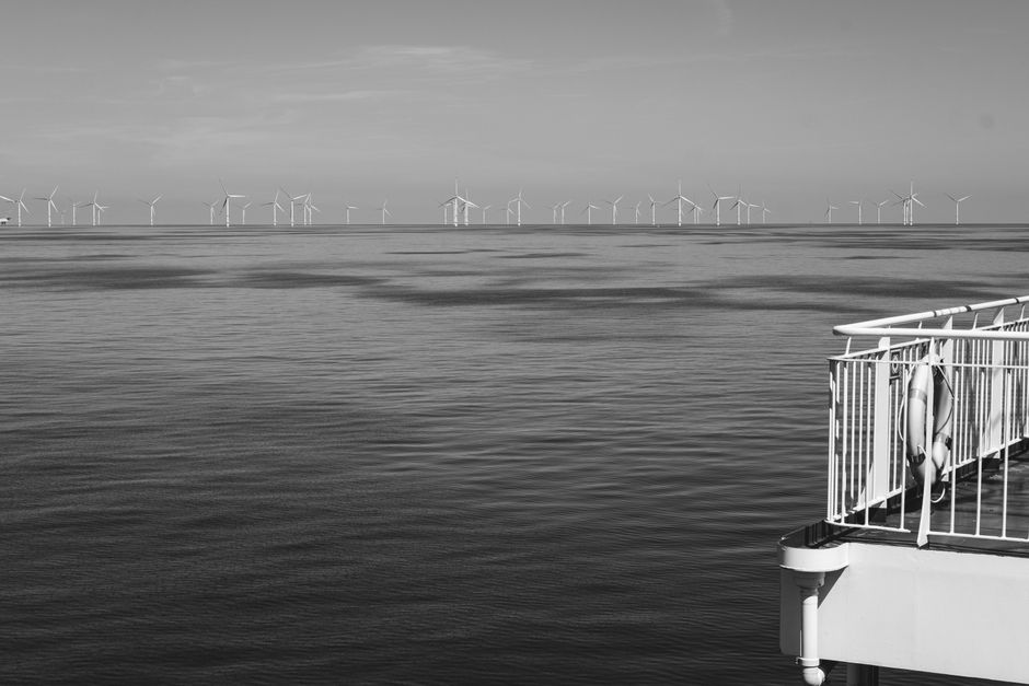 Black and white image of wind turbines in the ocean, symbolizing renewable energy.