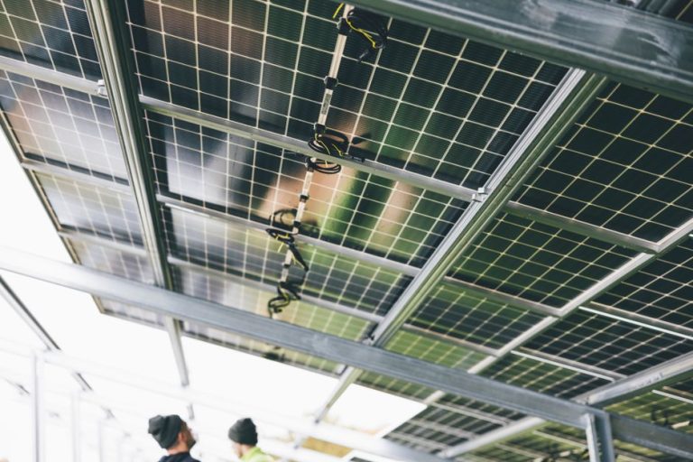 Close-up of solar panels being installed outdoors with technicians visible.