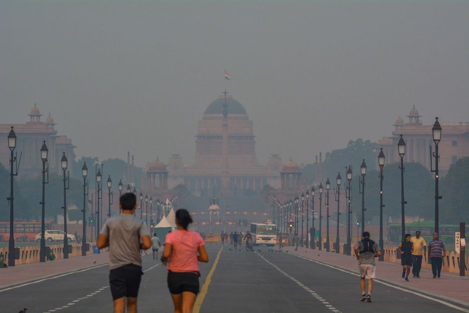 People jogging in smog near Rashtrapati Bhavan, New Delhi, highlighting urban pollution.