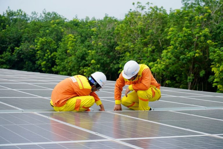 Workers installing photovoltaic solar panels on a sunny day, promoting renewable energy.