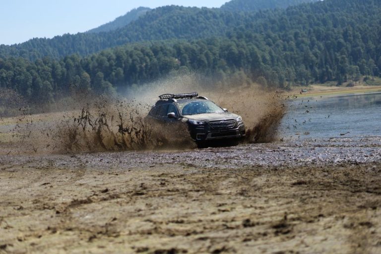 A rugged SUV powers through mud in a remote wilderness, showcasing adventure and offroad capabilities.