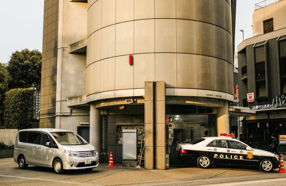 Street view featuring police and Nissan vehicles parked by a modern building.