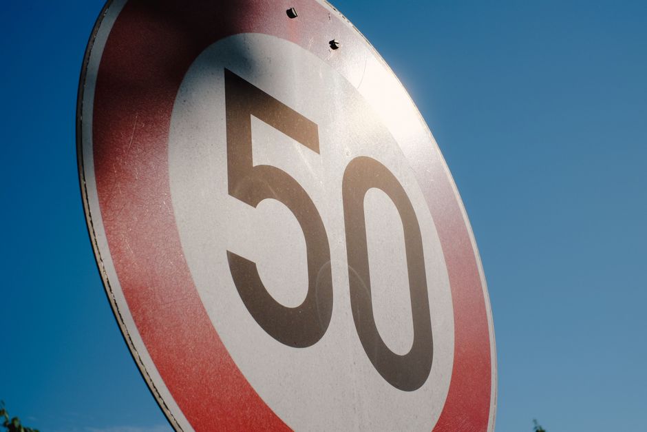 A close-up of a speed limit sign displaying 50 against a clear blue sky backdrop.