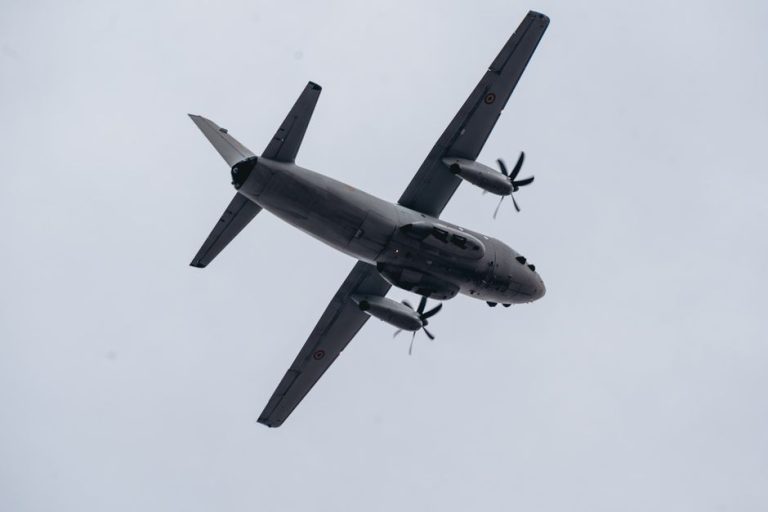 Low angle shot of a military aircraft flying against a gray sky in Bucharest, Romania.