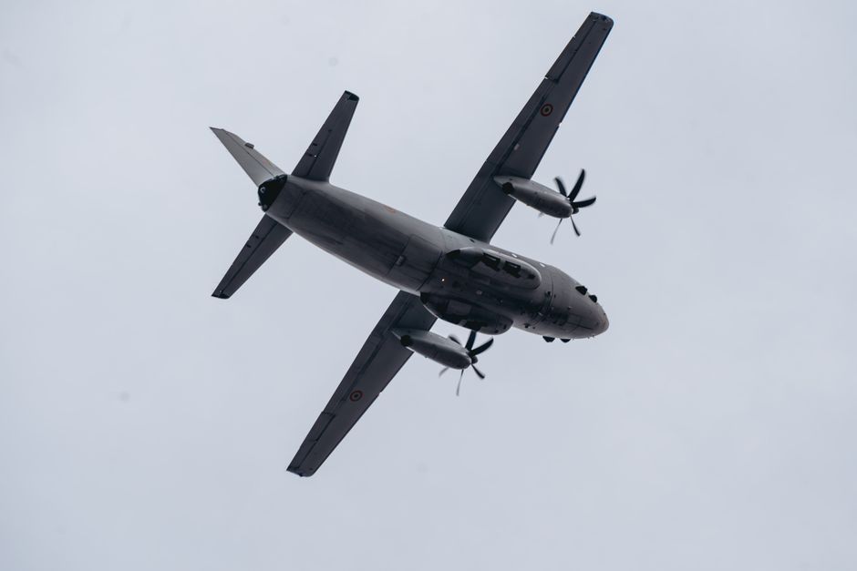 Low angle shot of a military aircraft flying against a gray sky in Bucharest, Romania.