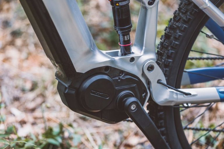 Detailed image of a modern bike's pedal and suspension in a forest setting.