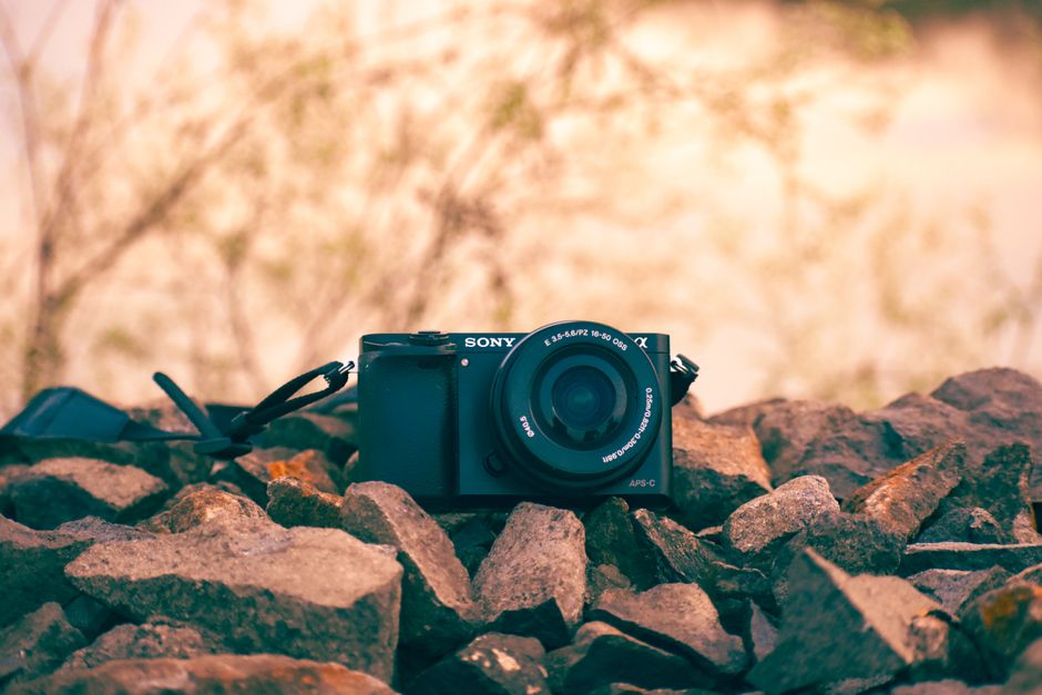 Sony camera placed on rocks outdoors, capturing natural essence in warm tones.