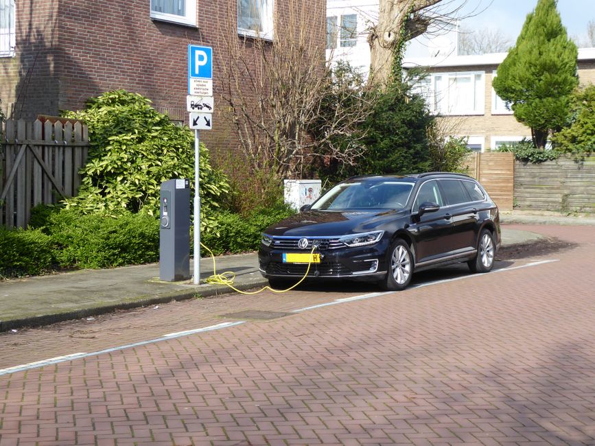 Electric car charging at a street station in Amsterdam, highlighting urban eco-friendliness.