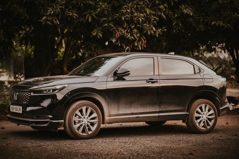 A stylish black Honda HR-V SUV parked outdoors amongst trees on a sunny day.