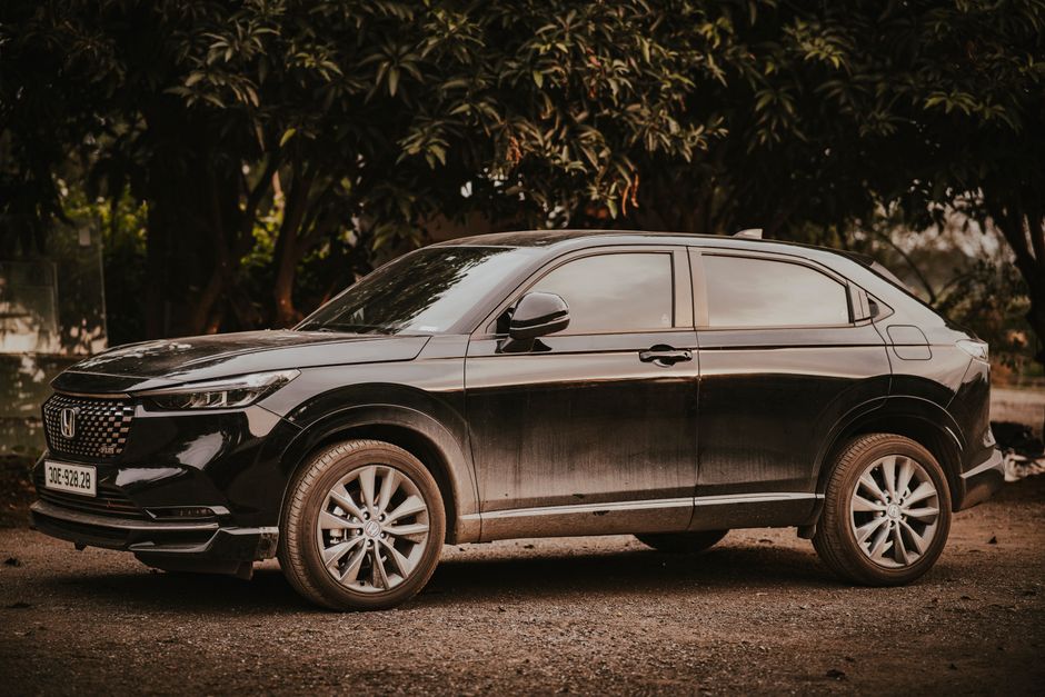 A stylish black Honda HR-V SUV parked outdoors amongst trees on a sunny day.