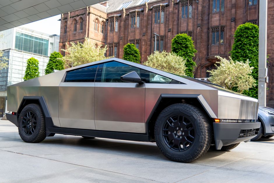 A modern electric truck parked in front of historic Manchester architecture.