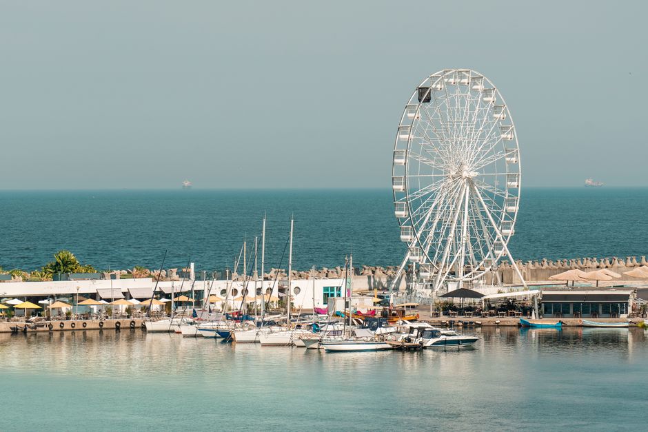 A vibrant view of a ferris wheel by the marina in Constanța, Romania.