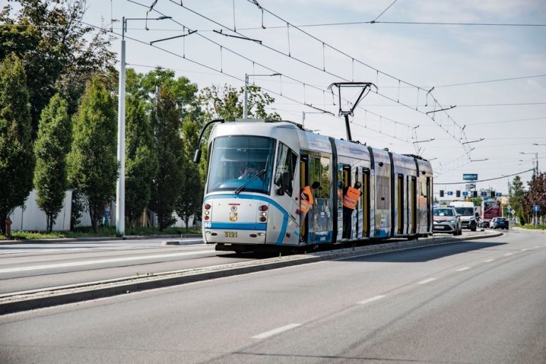 A sleek tram glides through Wrocław, Poland, showcasing city infrastructure and urban transport on a sunny day.