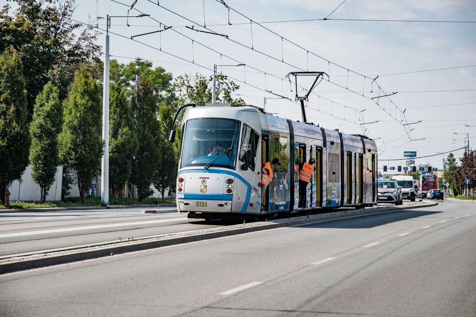 A sleek tram glides through Wrocław, Poland, showcasing city infrastructure and urban transport on a sunny day.