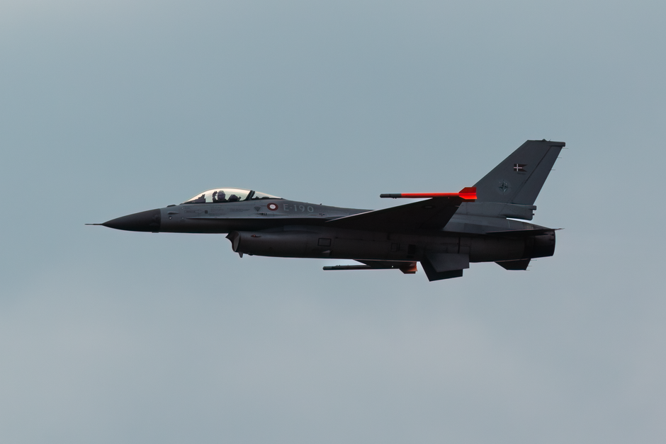 A sleek F-16 fighter jet soaring through a cloudy sky, showcasing military aviation