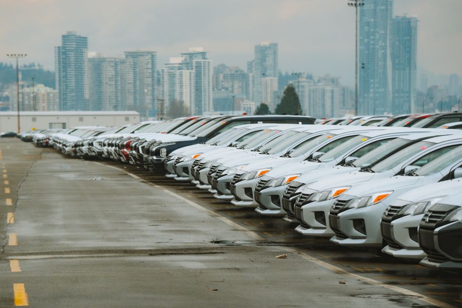 White cars lined up in a parking lot with a city skyline backdrop.