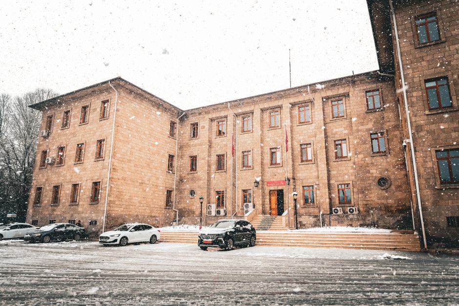 Snow-covered historic building with cars, showcasing winter ambiance.