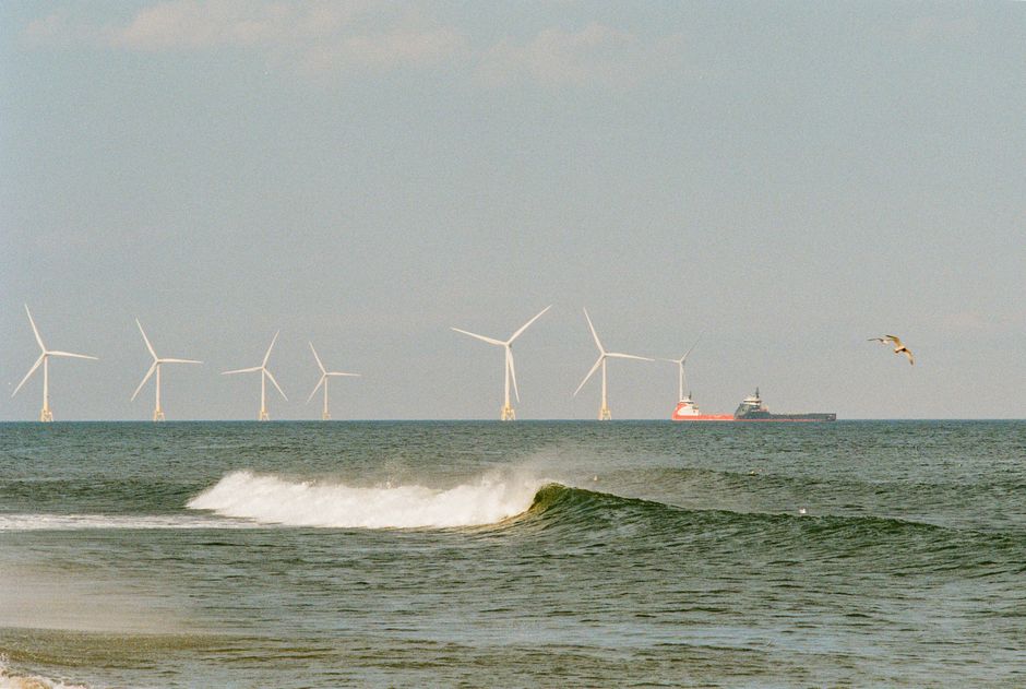 View of offshore wind turbines in the North Sea near Aberdeen, Scotland with a cargo ship and seagulls in the background.