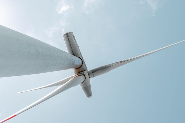 Looking up at a majestic wind turbine under a clear blue sky, showcasing renewable energy innovation.