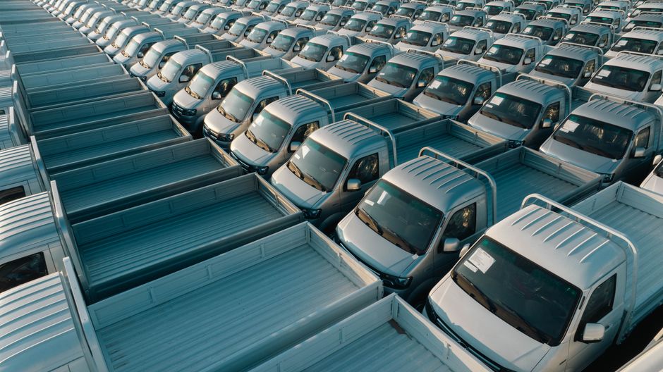 Aerial shot of multiple silver pickup trucks aligned in rows, showcasing symmetry and industrial production.