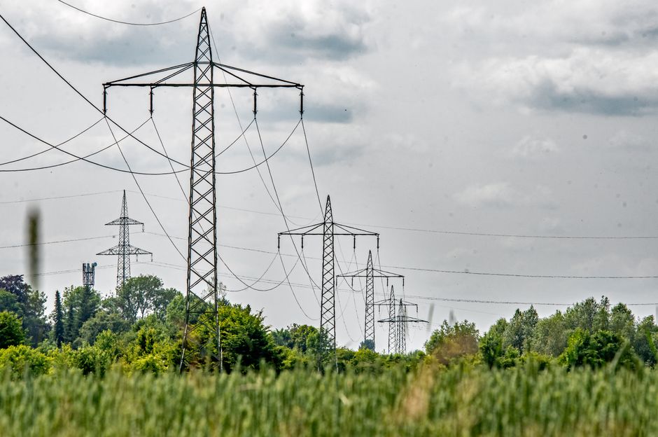 Transmission towers stretch across a lush field in Ingolstadt, Bavaria, Germany.