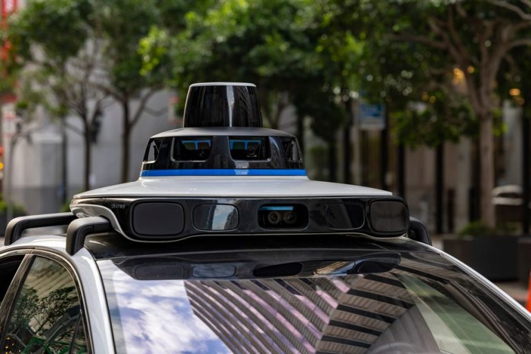 Detailed view of sensors atop an autonomous car, showcasing advanced technology in an urban setting.