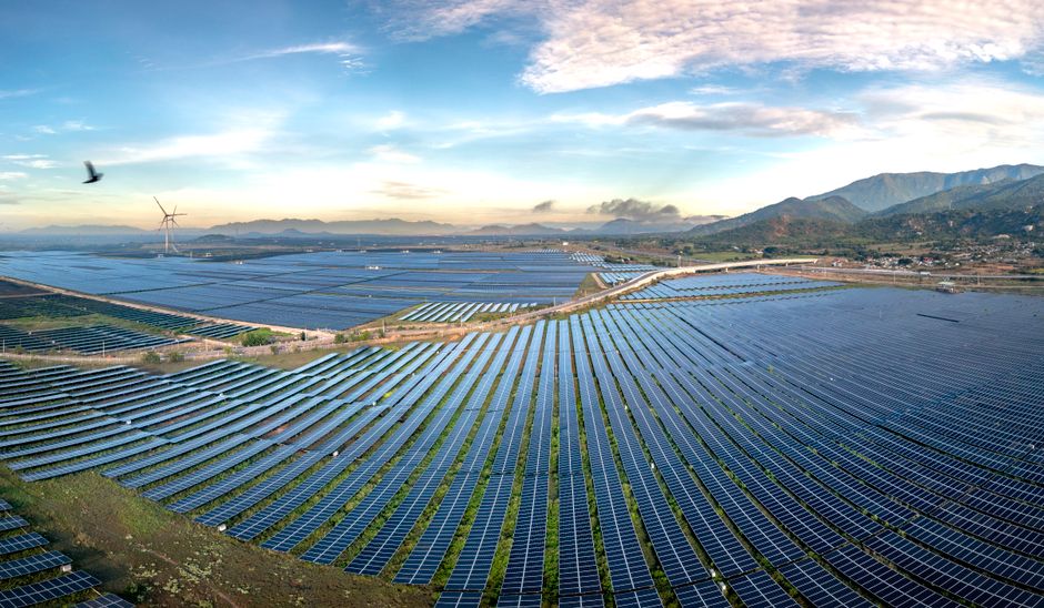 Aerial view of a vast solar farm with mountains and morning sky in Vietnam, symbolizing renewable energy.