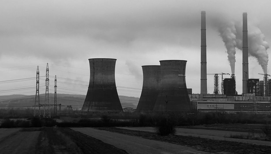Black and white view of a power plant in Turceni, Romania with cooling towers and chimneys.