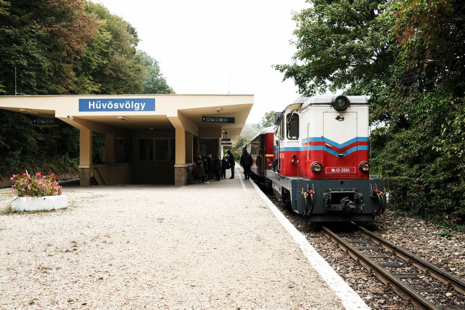 Vintage train at Hűvösvölgy station, Budapest, surrounded by lush greenery. A classic travel scene.