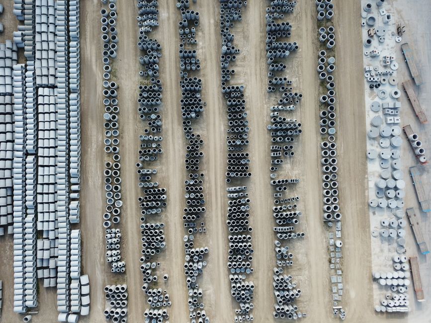Drone shot of an organized outdoor concrete manufacturing facility with various pipes.