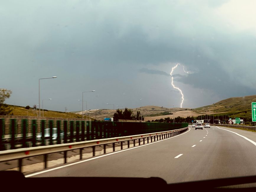 Dramatic lightning storm over a picturesque highway, captured from a moving car.