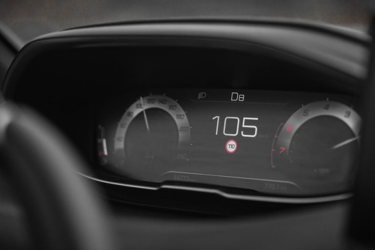 Close-up view of a digital car speedometer showing a speed of 105 in a modern vehicle dashboard.
