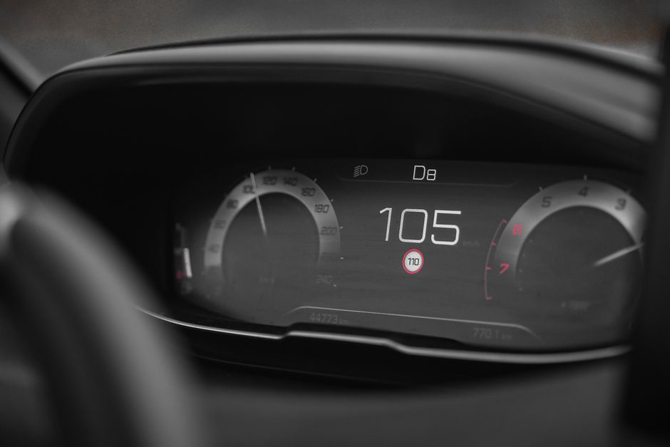 Close-up view of a digital car speedometer showing a speed of 105 in a modern vehicle dashboard.