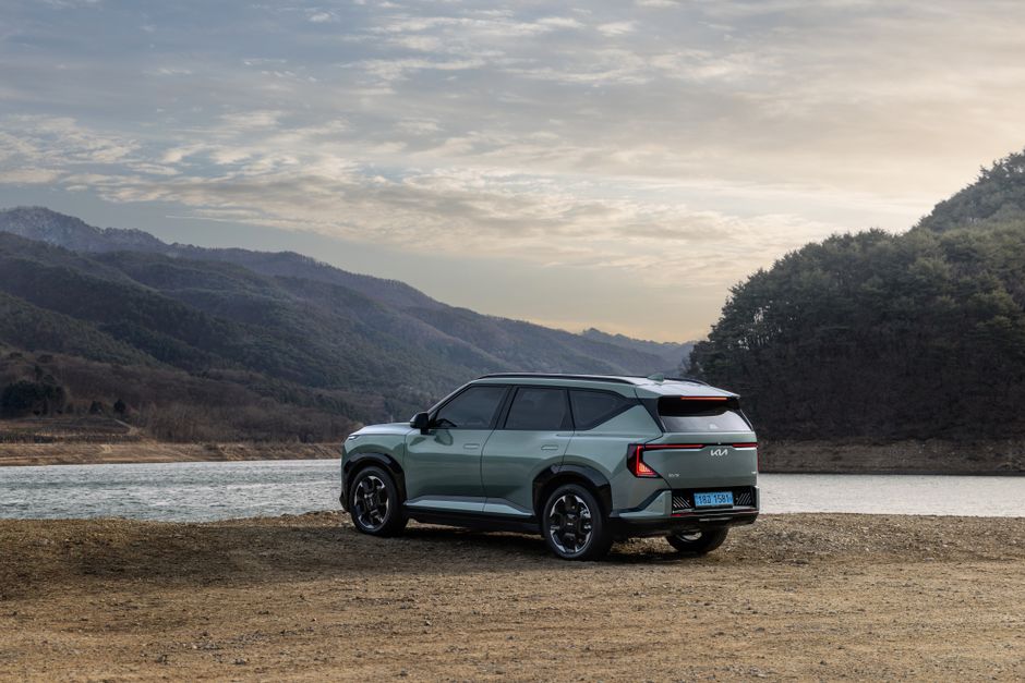 A modern electric SUV parked by a tranquil mountain lake with scenic views of nature.