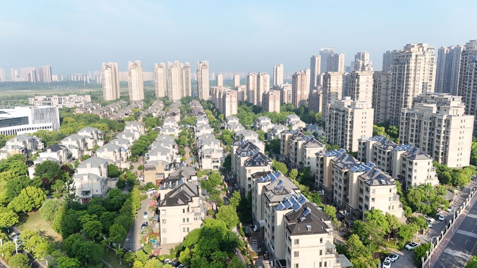 Aerial view of modern residential area with high-rise apartments and greenery on a sunny day.