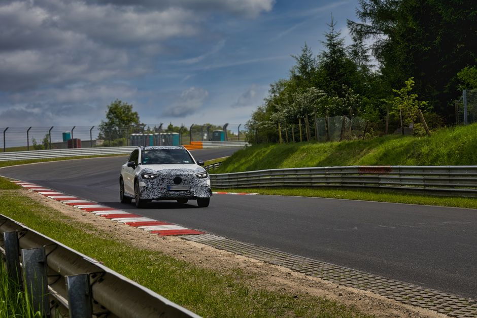 Camouflaged sports car driving on the iconic Nurburgring race track.