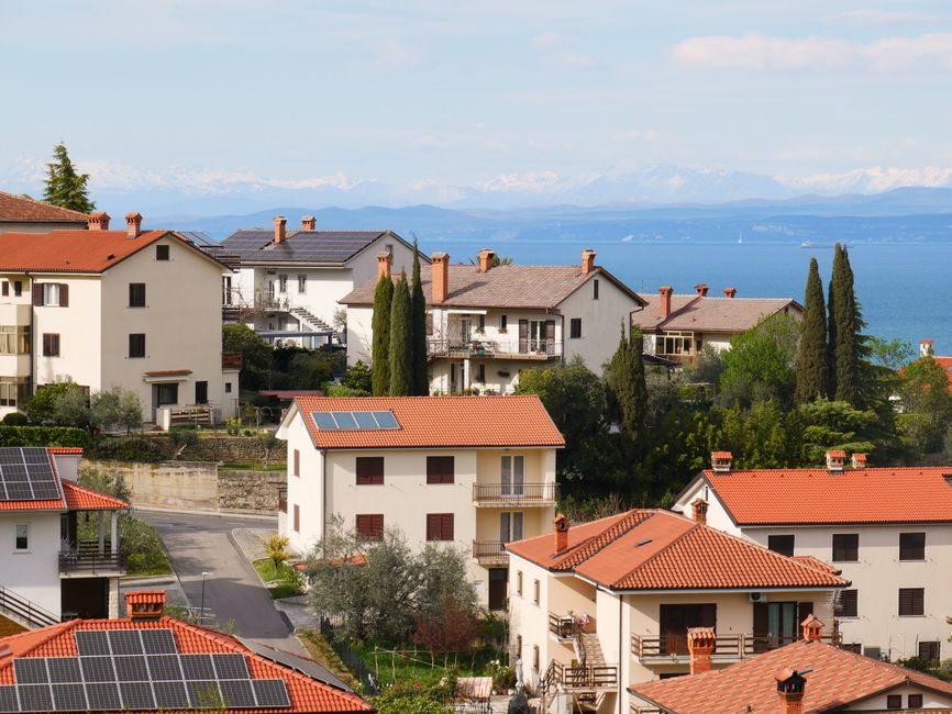 Picturesque Mediterranean village with red-tiled roofs and sea view, showcasing serene coastal living.