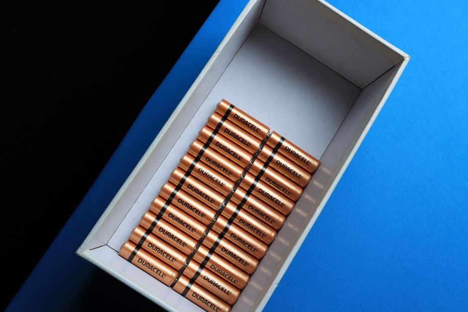 Top view of neatly arranged batteries in a box on a contrasting blue surface.