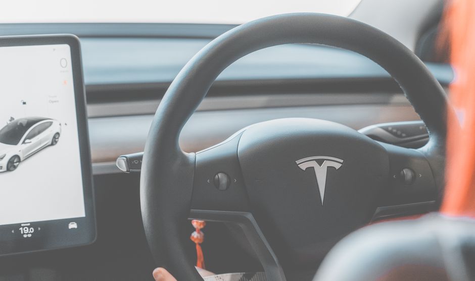 Close-up view of a Tesla electric car steering wheel and digital display, showcasing modern automotive design.
