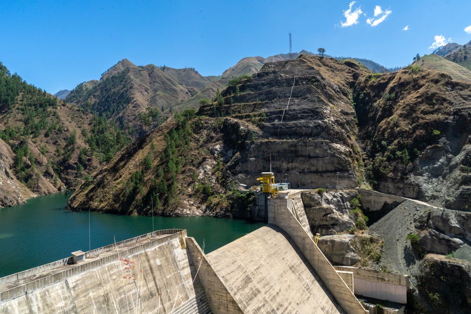 Picturesque hydroelectric dam nestled in a mountainous landscape under a clear blue sky.
