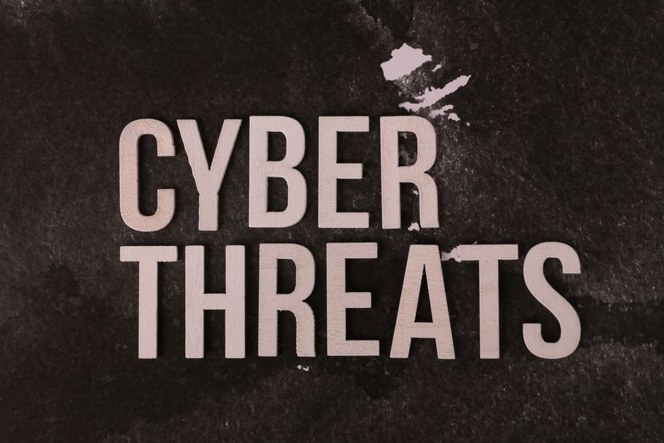 The phrase 'Cyber Threats' displayed on a textured dark background, emphasizing digital security.