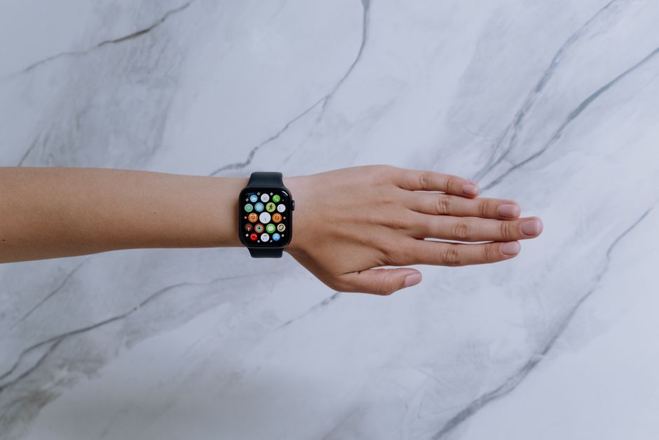 Overhead view of a smartwatch on an arm against a marble background representing modern technology.