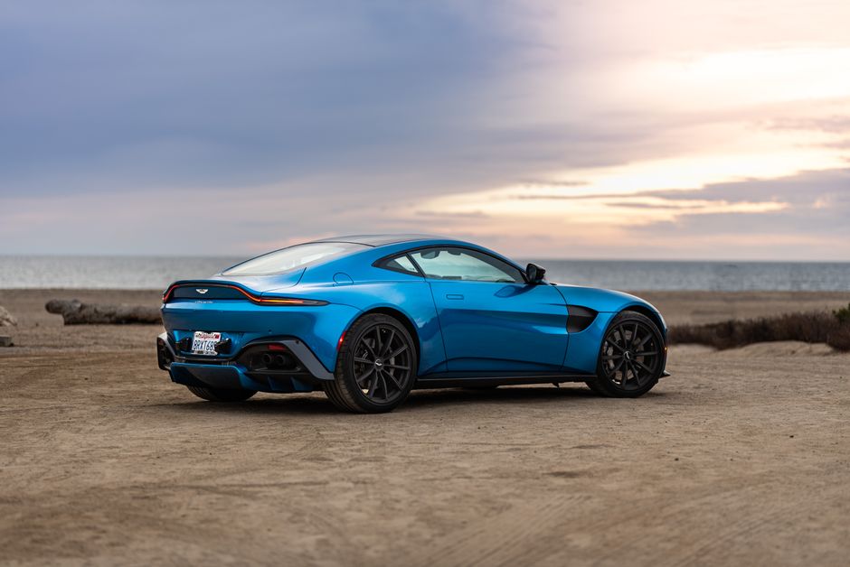 A sleek blue sports car parked near the ocean, exuding luxury and style in a serene seaside setting.