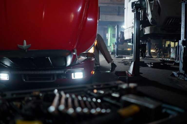 Mechanic working on a truck in a dimly lit garage, focused on repair and maintenance.