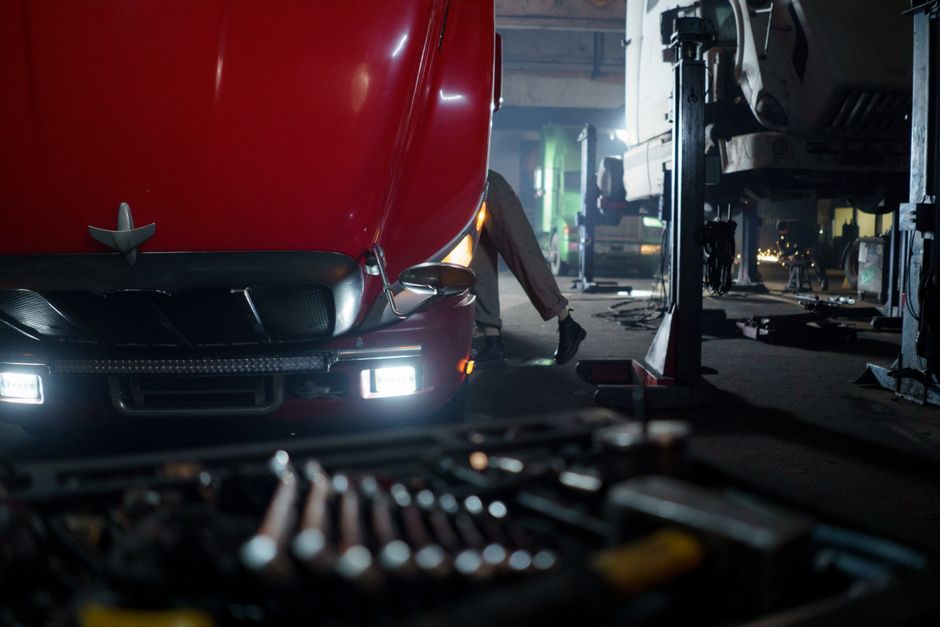 Mechanic working on a truck in a dimly lit garage, focused on repair and maintenance.